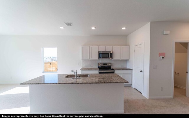 kitchen with sink, light carpet, a kitchen island with sink, white cabinets, and appliances with stainless steel finishes