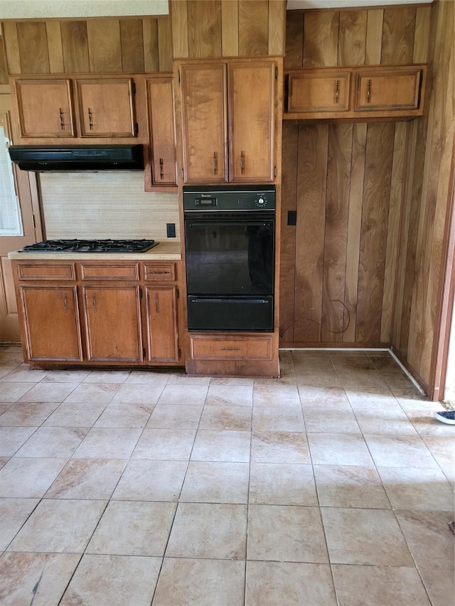 kitchen featuring extractor fan, stainless steel gas cooktop, and wooden walls