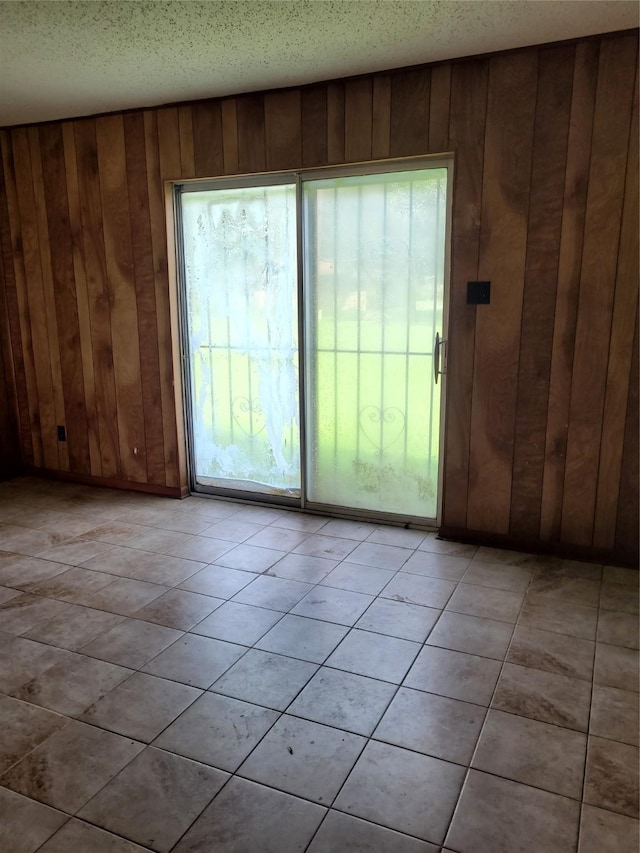 doorway with a textured ceiling, a wealth of natural light, and wood walls