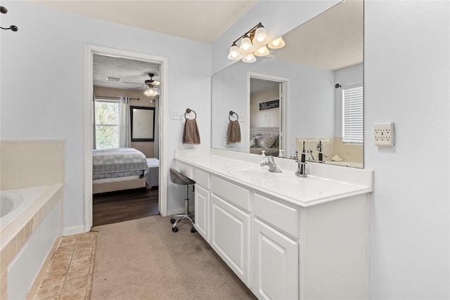 bathroom featuring ceiling fan, vanity, and a relaxing tiled tub