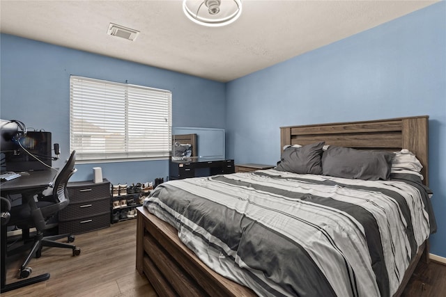 bedroom with a textured ceiling and dark hardwood / wood-style floors