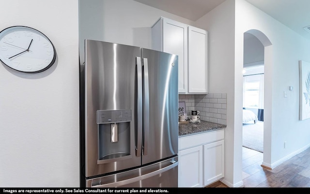 kitchen with stainless steel fridge with ice dispenser, white cabinetry, and dark stone counters