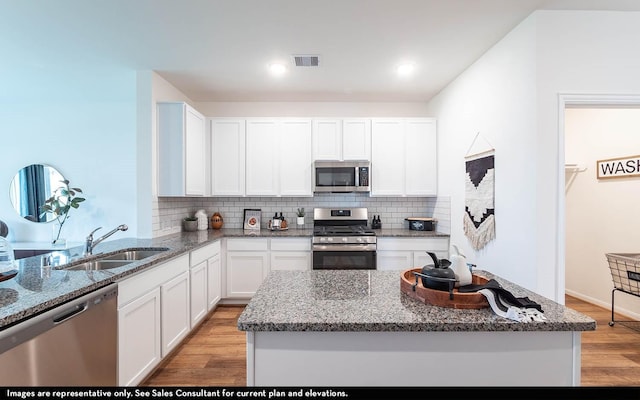 kitchen with white cabinetry, sink, stainless steel appliances, and light hardwood / wood-style flooring