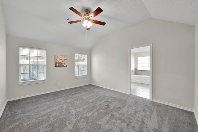 unfurnished room featuring a wealth of natural light, light colored carpet, and vaulted ceiling