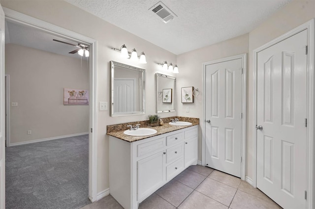 bathroom with tile patterned floors, ceiling fan, vanity, and a textured ceiling