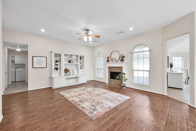 unfurnished living room featuring a textured ceiling, ceiling fan, washer and clothes dryer, and dark hardwood / wood-style floors