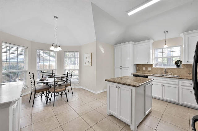 kitchen with white cabinets, sink, a kitchen island, and vaulted ceiling