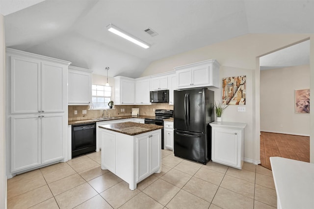 kitchen featuring lofted ceiling, dark stone counters, black appliances, a kitchen island, and white cabinetry