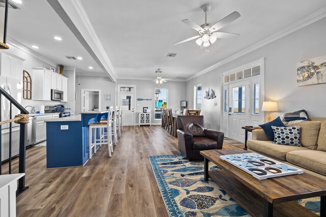 living room featuring hardwood / wood-style flooring, ceiling fan, and ornamental molding