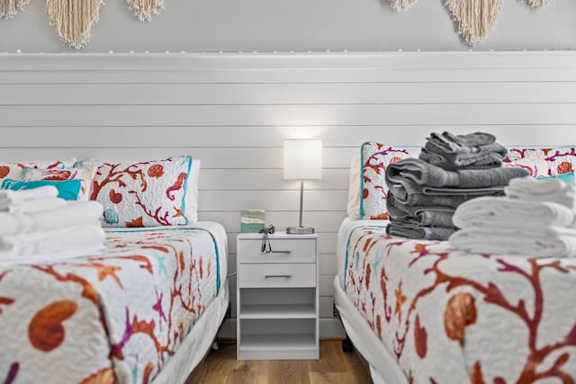 bedroom with hardwood / wood-style flooring and wooden walls