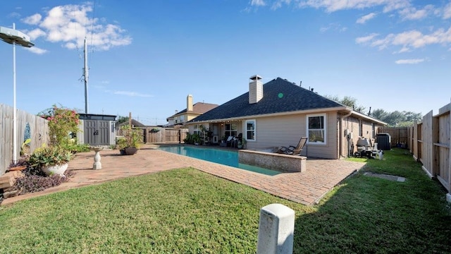 back of house featuring central air condition unit, a yard, a patio, a fenced in pool, and a shed