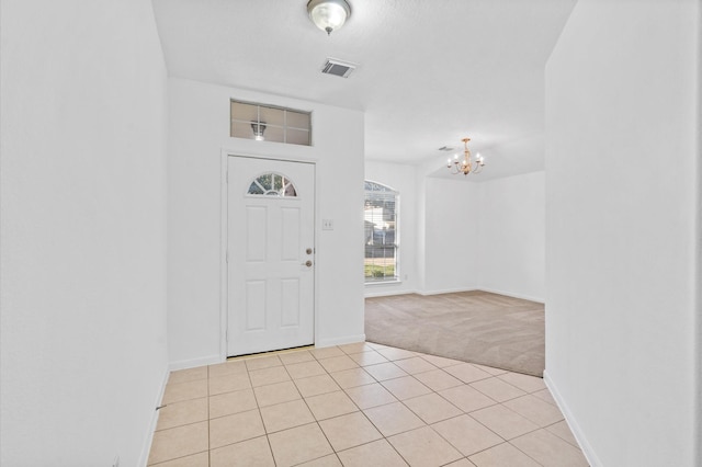 foyer featuring light colored carpet and an inviting chandelier