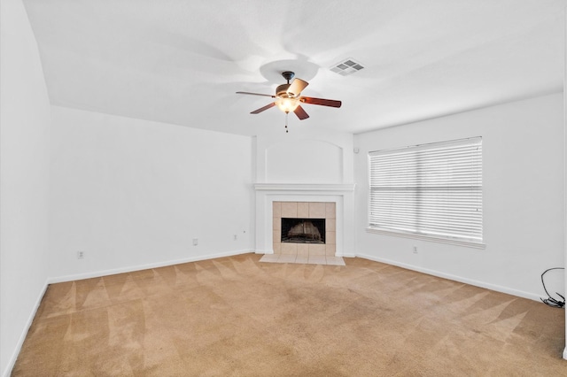 unfurnished living room with a tile fireplace, light carpet, and ceiling fan