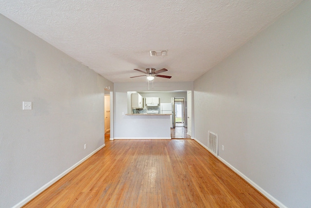 unfurnished living room with a textured ceiling, light hardwood / wood-style floors, and ceiling fan