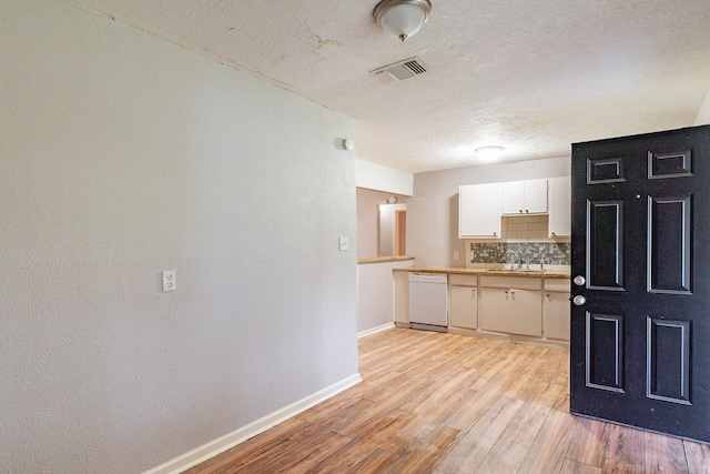 kitchen featuring dishwasher, sink, tasteful backsplash, light hardwood / wood-style floors, and white cabinetry