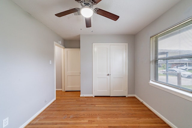 unfurnished bedroom featuring ceiling fan, light wood-type flooring, and a closet