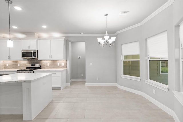 kitchen with white cabinets, decorative light fixtures, light stone counters, and appliances with stainless steel finishes