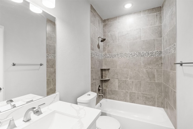 full bathroom featuring vanity, tiled shower / bath, and toilet