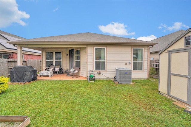 rear view of property with central AC unit, a shed, a patio, and a lawn