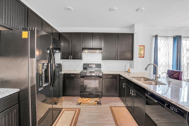 kitchen with black appliances, light stone countertops, sink, and light hardwood / wood-style flooring