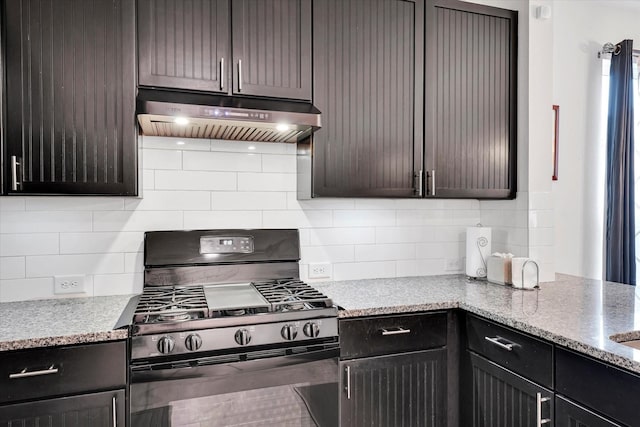 kitchen featuring tasteful backsplash, light stone counters, dark brown cabinets, and black range with gas cooktop