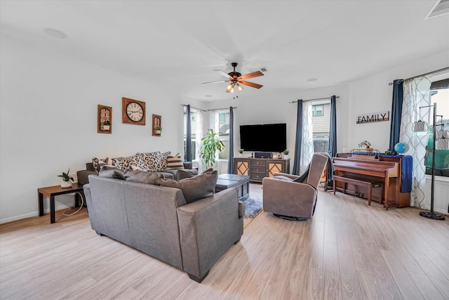 living room with light wood-type flooring, ceiling fan, and a healthy amount of sunlight