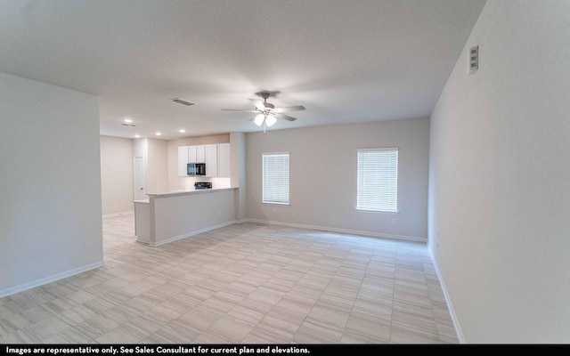 unfurnished living room featuring ceiling fan and a textured ceiling