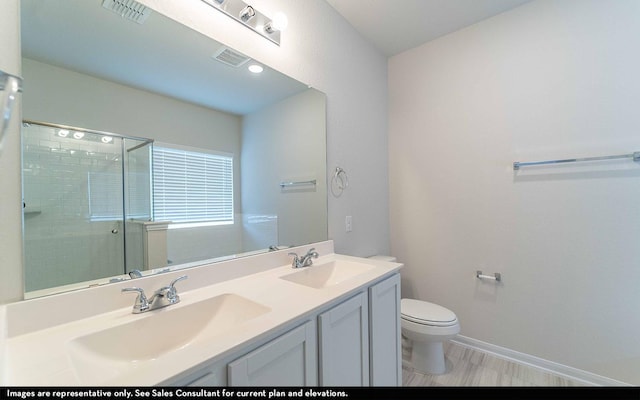 bathroom with hardwood / wood-style floors, vanity, toilet, and a shower with door