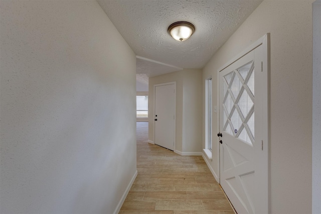 doorway with a textured ceiling and light hardwood / wood-style floors