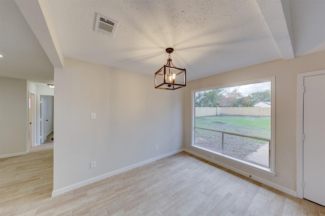 interior space featuring beamed ceiling, light hardwood / wood-style floors, a textured ceiling, and an inviting chandelier