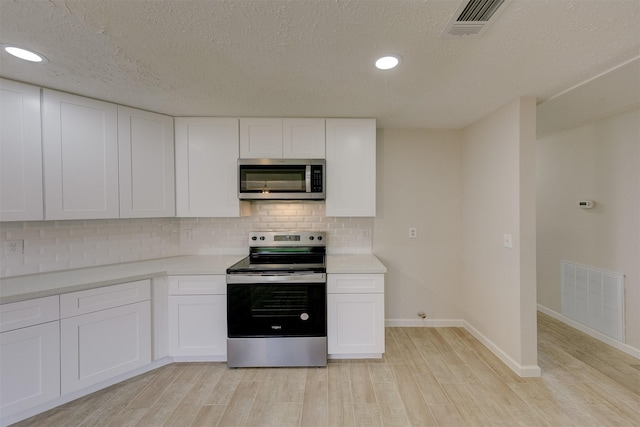 kitchen featuring light wood-type flooring, a textured ceiling, tasteful backsplash, white cabinetry, and stainless steel appliances