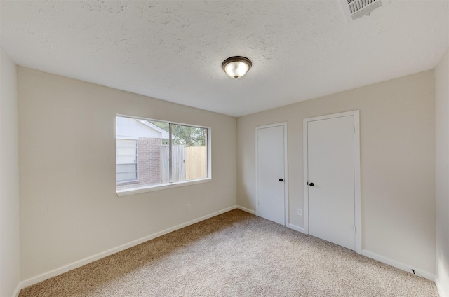 unfurnished bedroom with light carpet and a textured ceiling