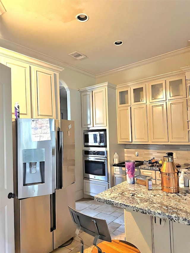 kitchen featuring light stone countertops, appliances with stainless steel finishes, backsplash, and ornamental molding