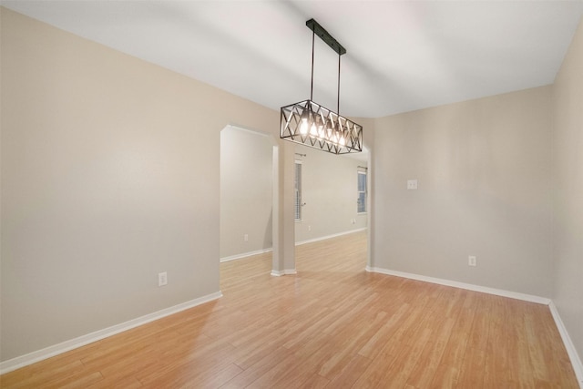 unfurnished room with light wood-type flooring and a notable chandelier