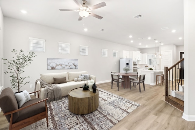 living room featuring ceiling fan, light hardwood / wood-style floors, and sink