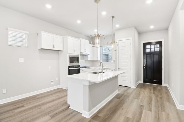 kitchen with pendant lighting, white cabinets, sink, built in microwave, and wall oven