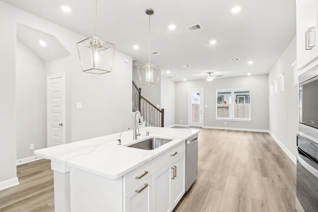 kitchen with stainless steel appliances, ceiling fan, sink, a center island with sink, and white cabinets