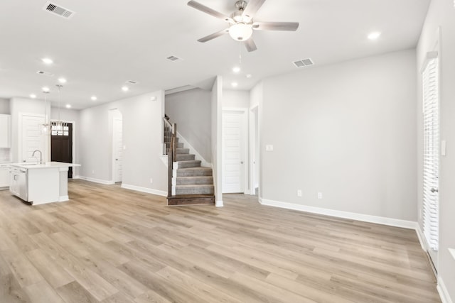 unfurnished living room with ceiling fan, sink, and light hardwood / wood-style floors