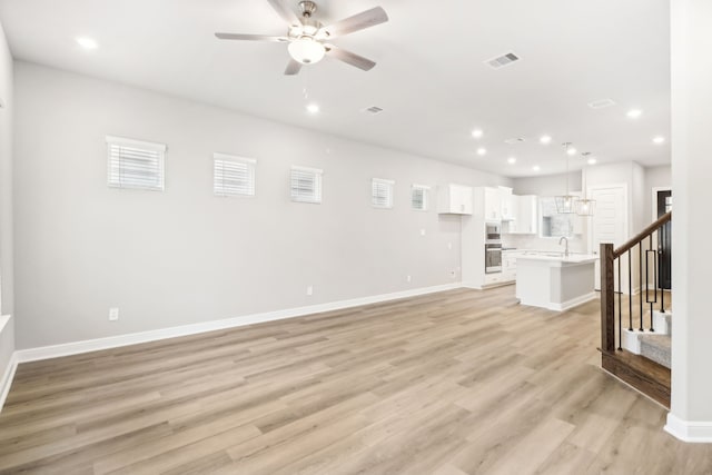 unfurnished living room with ceiling fan, light hardwood / wood-style flooring, and sink