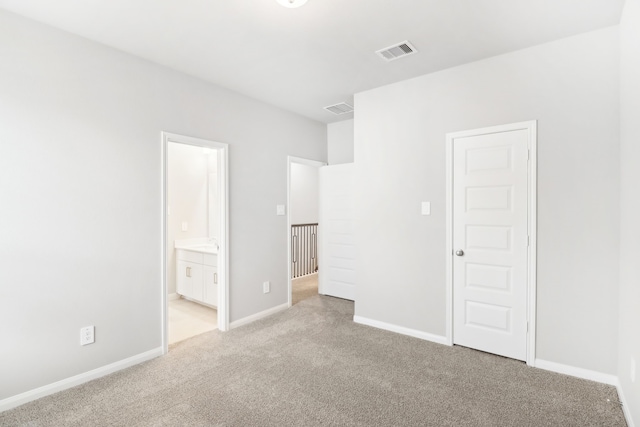 unfurnished bedroom with connected bathroom, light colored carpet, and a closet