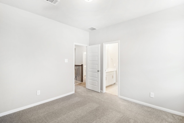 unfurnished bedroom featuring light carpet and ensuite bath