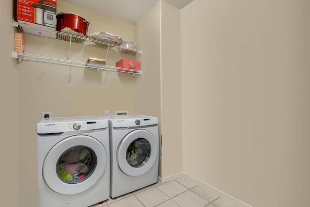 clothes washing area featuring washer and clothes dryer and light tile patterned flooring