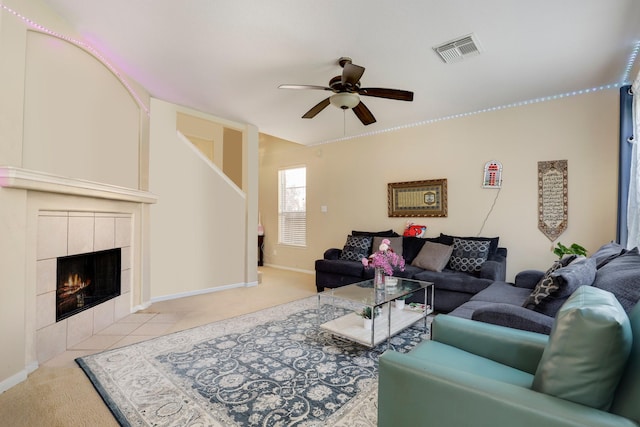 carpeted living room with a tiled fireplace and ceiling fan