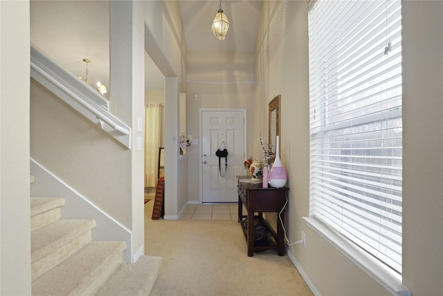 carpeted foyer entrance featuring a healthy amount of sunlight and a chandelier