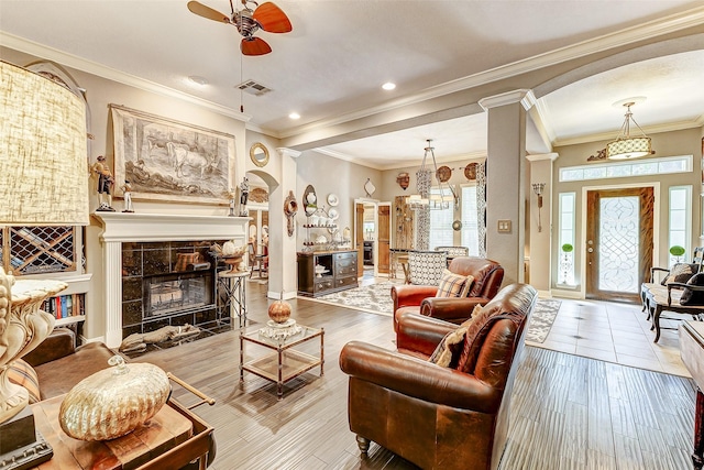 living room with arched walkways, visible vents, a tile fireplace, and wood finished floors