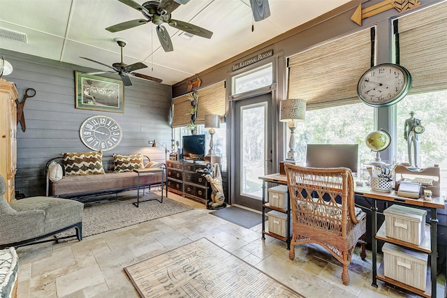 living area featuring visible vents, wood walls, and stone tile floors