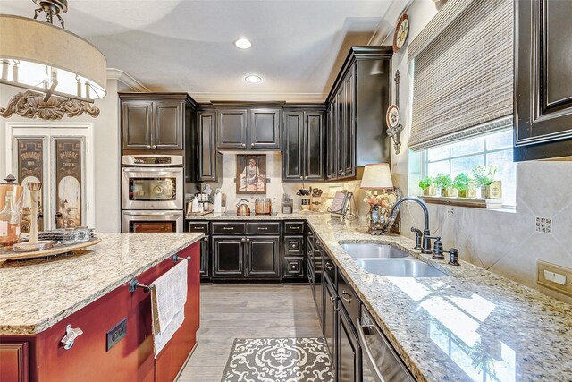 kitchen with sink, light hardwood / wood-style flooring, double oven, crown molding, and pendant lighting