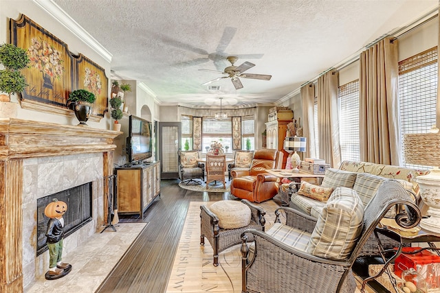 living area featuring ornamental molding, visible vents, a fireplace, and light wood finished floors