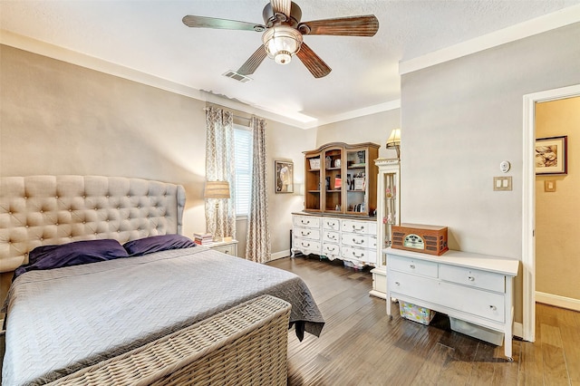 bedroom with ceiling fan, wood-type flooring, a textured ceiling, and ornamental molding