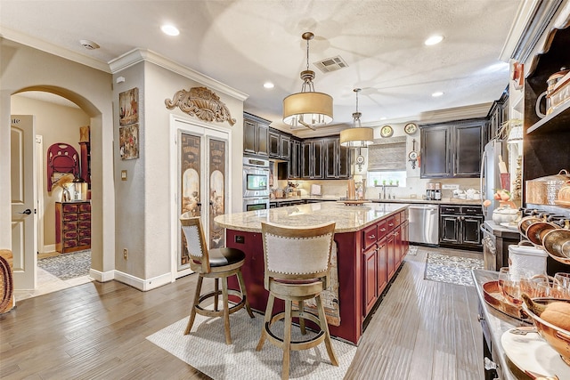 kitchen featuring arched walkways, crown molding, visible vents, appliances with stainless steel finishes, and a kitchen island